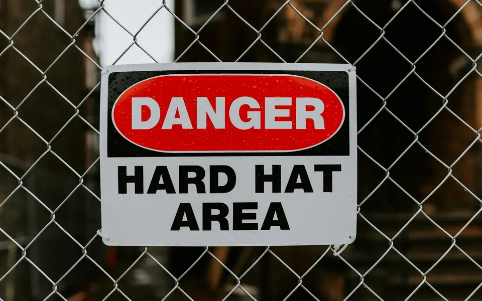 Danger hard hat area sign on a site fence