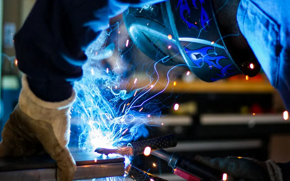 Welder in a helmet and gloves welding steel